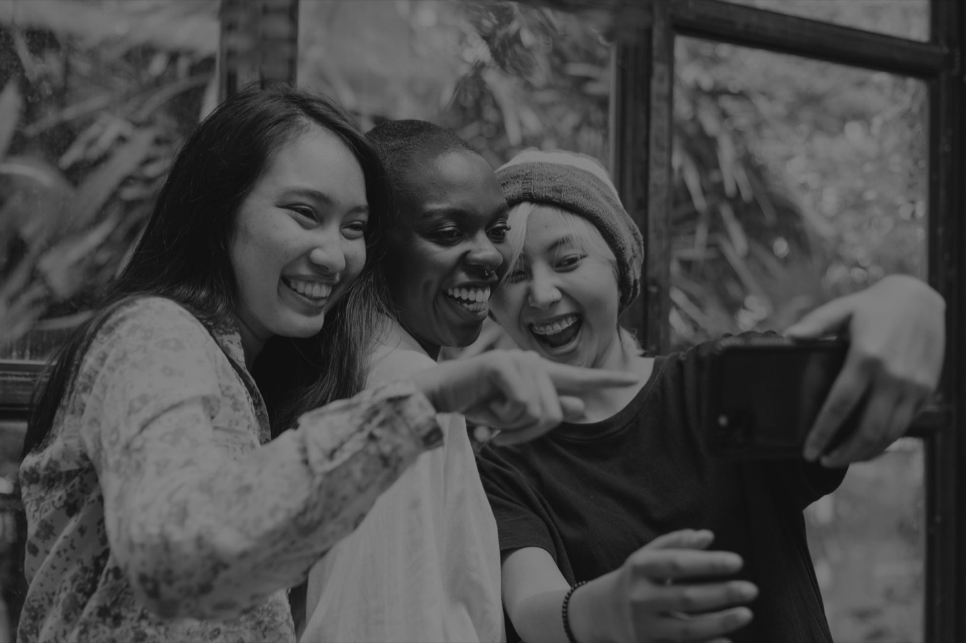 Three friends laughing while taking a selfie together